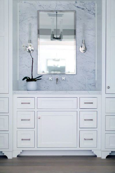 White vanity with marble backsplash, chrome hardware, and single mirror.