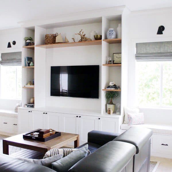Modern living room with built-in bookcases, floating shelves, TV centerpiece, and cozy seating with natural light