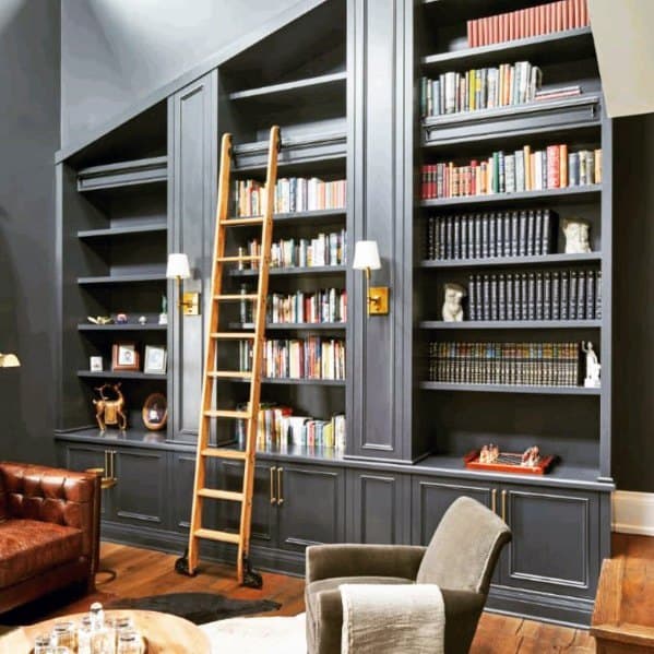 Stylish home library with dark bookshelves, books, ladder, leather chair, and accent lighting