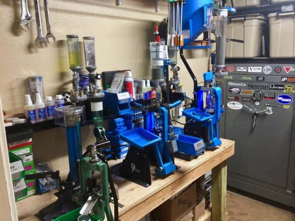 Fully equipped reloading bench with multiple blue presses, tools, and organized storage, creating a streamlined workspace