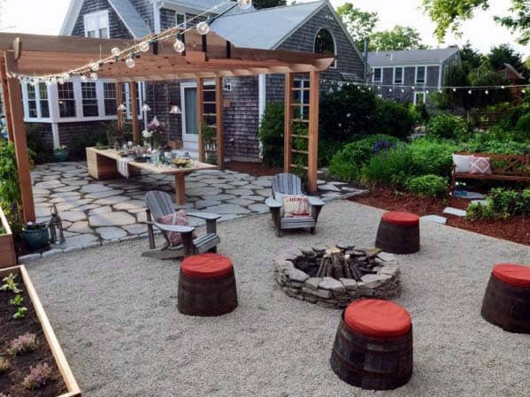 Backyard with fire pit, Adirondack chairs, wooden stools, a pergola, overhead string lights, and garden beds