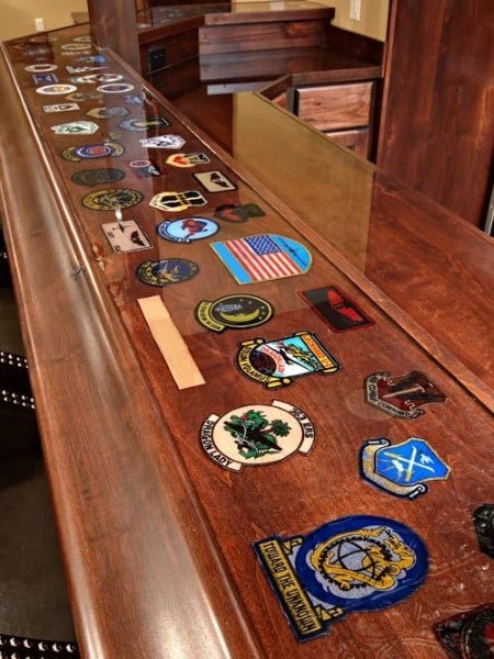 Wooden bar top with embedded military and American patches under a clear epoxy finish.