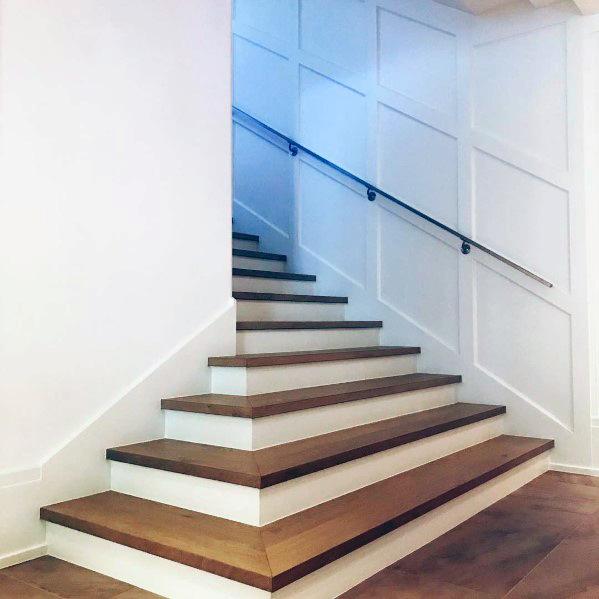 Staircase with wide wooden steps and sleek handrail in a bright modern interior.