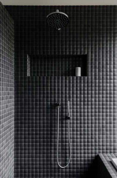 Black tiled shower with built-in shelf and modern rainfall showerhead.