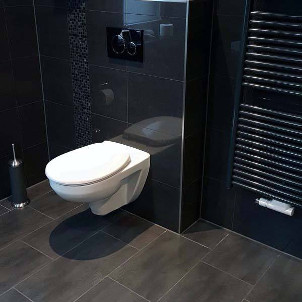 Black bathroom with wall-mounted white toilet, mosaic accent, and heated towel rail.