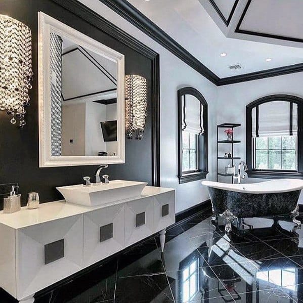 Modern black and white bathroom with crystal wall sconces, freestanding tub, and glossy floors.