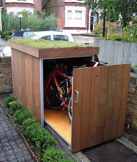 Compact wooden outdoor bike shed with a green roof, ideal for secure bicycle storage.
