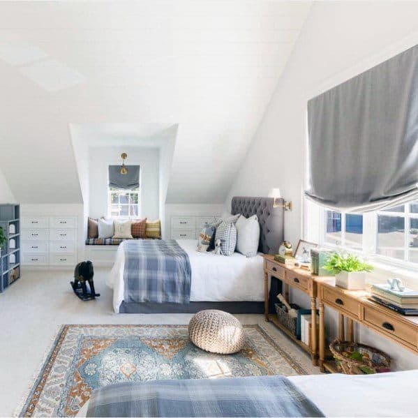 Bright attic bedroom with twin beds, cozy seating nook, and decorative area rug.
