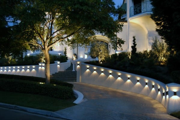 Elegant driveway with low wall-mounted lights, illuminating the path and enhancing the landscape with soft, ambient lighting at dusk