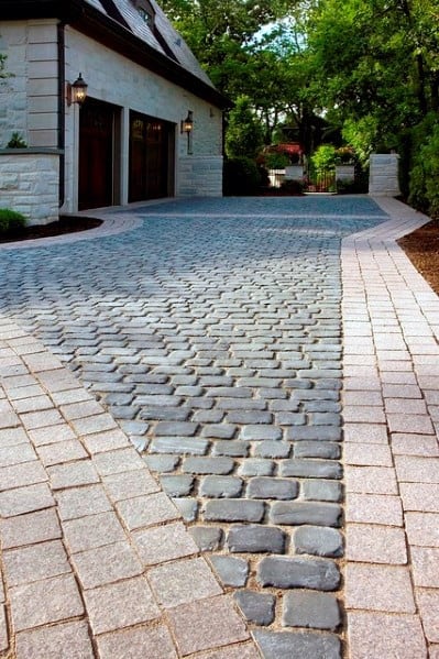 Cobblestone driveway with light brick borders, creating a classic and refined appearance.