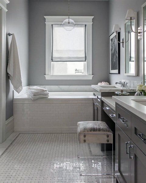 Modern bathroom with picture-frame mirror, soaking tub, and gray vanity with marble countertop.