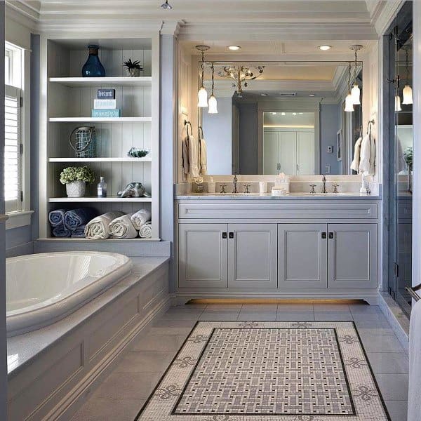 Elegant bathroom with built-in shelves, soaking tub, and large vanity mirror with pendant lights.