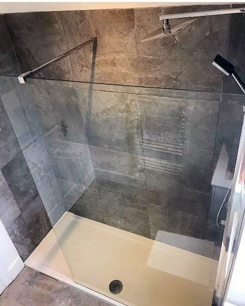 Modern shower with glass walls, grey tiles, and a sleek white base