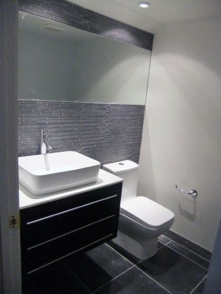 gray tile accent wall with mirror in small bathroom