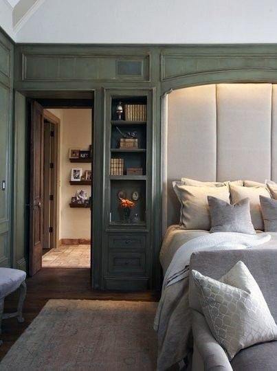 Bedroom with built-in green shelves, upholstered headboard, and neutral bedding.