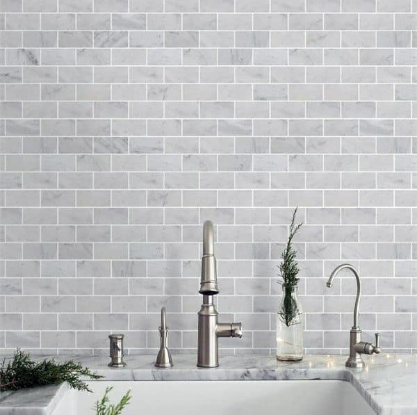 Marble subway tile backsplash with stainless steel faucet and marble countertop.