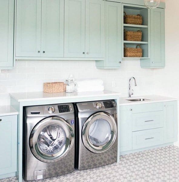 Laundry room with mint green cabinets, stainless steel appliances, and patterned tile flooring.