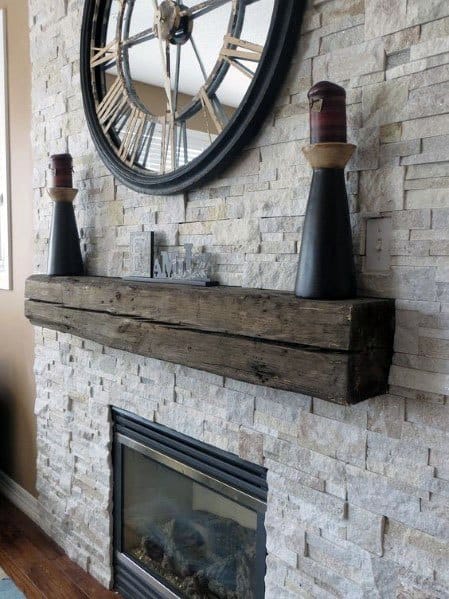 Rustic stacked stone fireplace with a reclaimed wood mantel and decorative clock centerpiece
