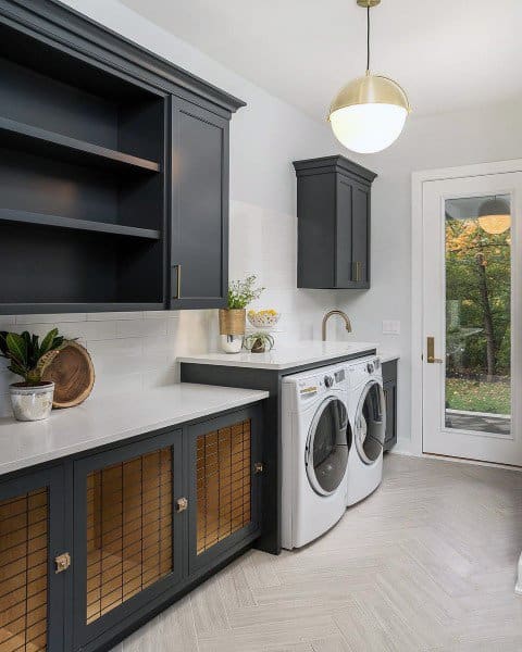 Laundry room with dark cabinets, white appliances, herringbone flooring, and a glass door.
