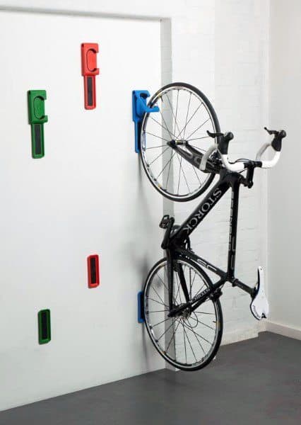 Colorful vertical wall hooks for efficient bicycle storage in compact spaces.