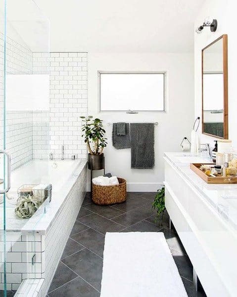 Modern bathroom with white tiles, a white bathtub, plants, towel rack, and a vanity