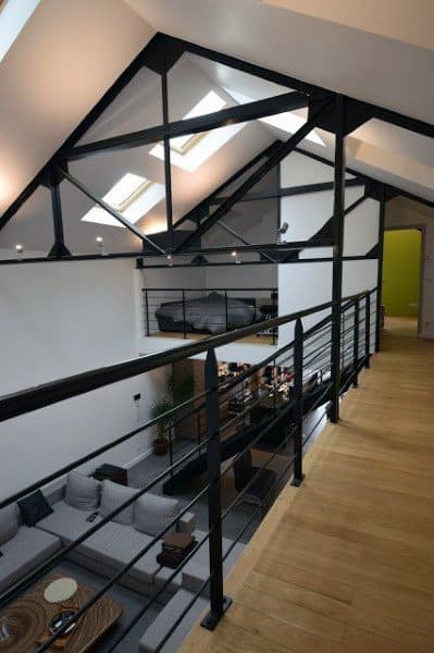 Loft with exposed black metal beams, sleek railings, skylights, and a contemporary minimalist design.