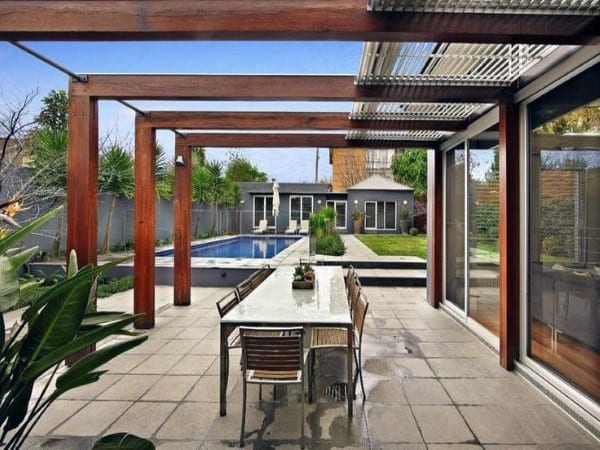 Modern pergola with wooden beams, outdoor dining area, and a poolside patio setting.