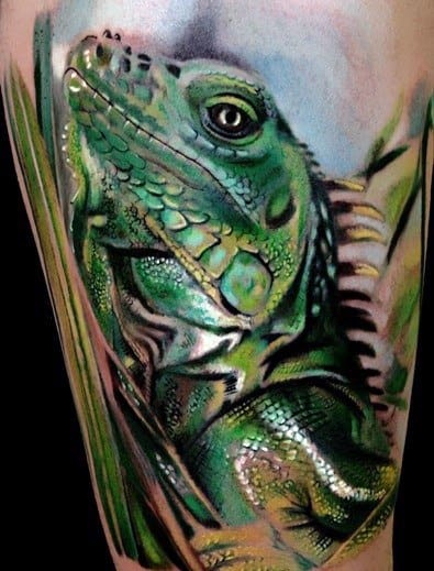 Lifelike green iguana tattoo with shimmering scales, surrounded by soft shading and leafy elements for a natural jungle look.
