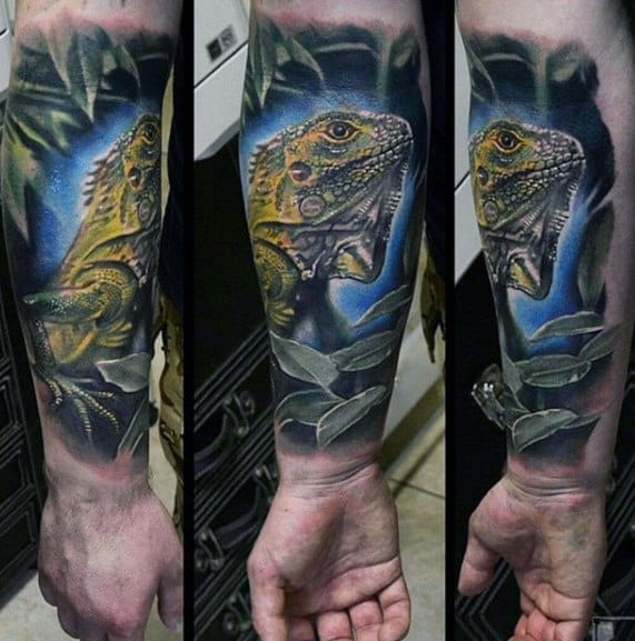 Bright yellow and green iguana forearm tattoo with a vivid blue background, surrounded by shaded leaves and realistic depth.