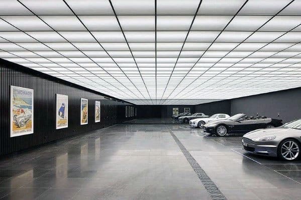 Luxury garage with illuminated grid ceiling, sleek black flooring, and modern sports cars.