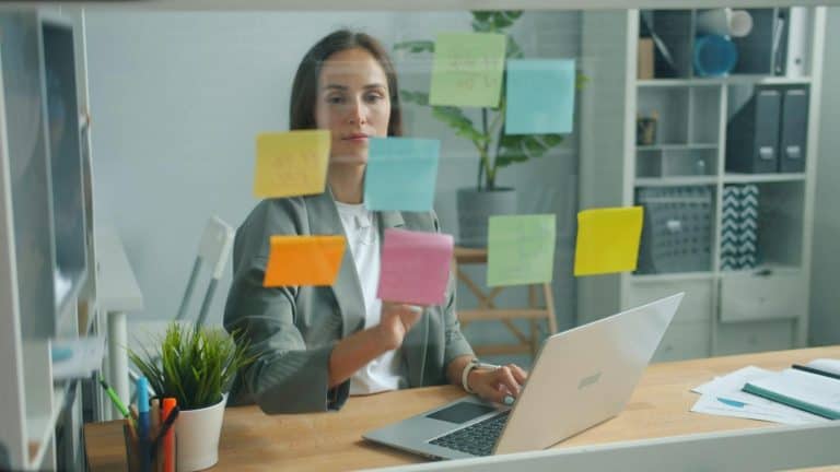 A modern professional sits at her desk, efficiently delegating research with colorful sticky notes in a sleek office setting
