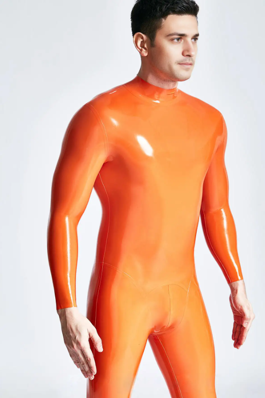 A man wears a shiny, vibrant orange latex bodysuit in front of a plain light background, showcasing bold latex fashion trends
