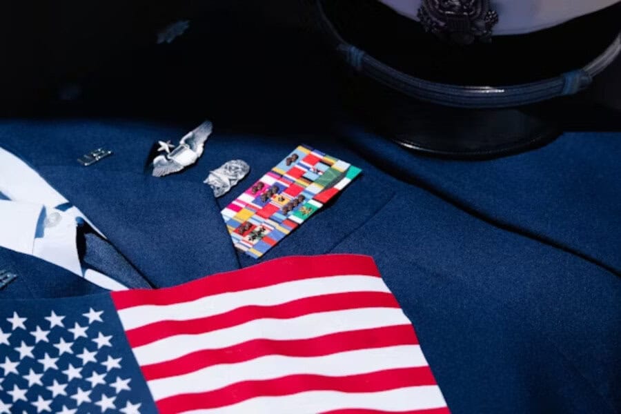 US flag draped over a decorated military uniform with medals and a dress cap, honoring veterans with patriotic pride