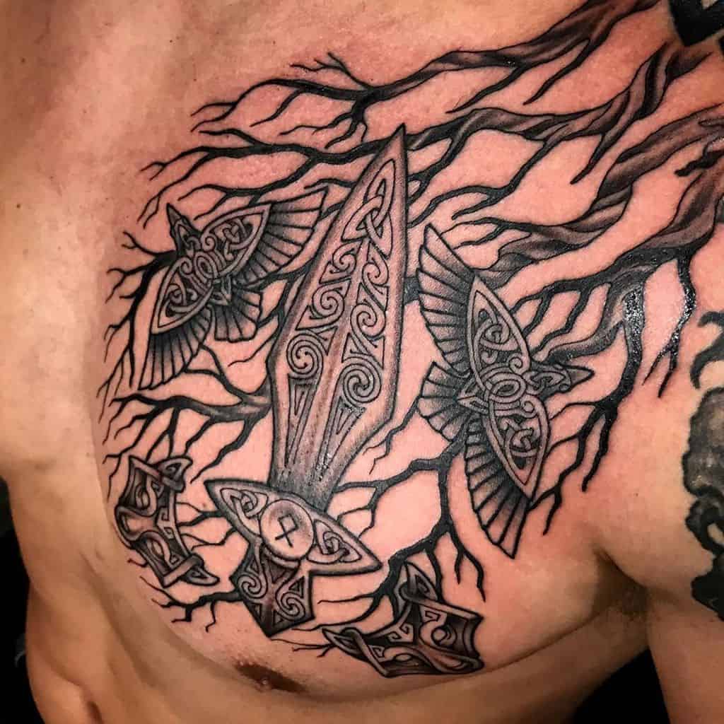 Yggdrasil chest tattoo with a Norse sword, ravens, and Mjölnir, symbolizing strength, wisdom, and Viking heritage.