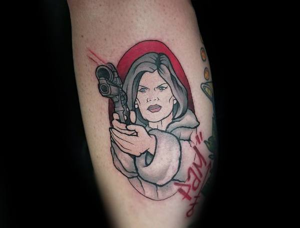 Bold Malory Archer tattoo featuring her in a fur coat aiming a gun, with a red background and sharp linework capturing her fierce expression.
