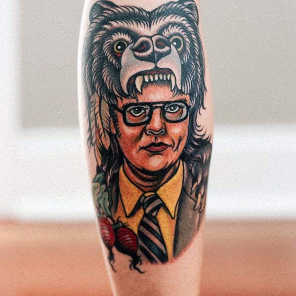 Tattoo of Dwight Schrute wearing a fierce bear headdress, featuring bold colors, detailed shading, and beets on the side, blending realism and traditional style.