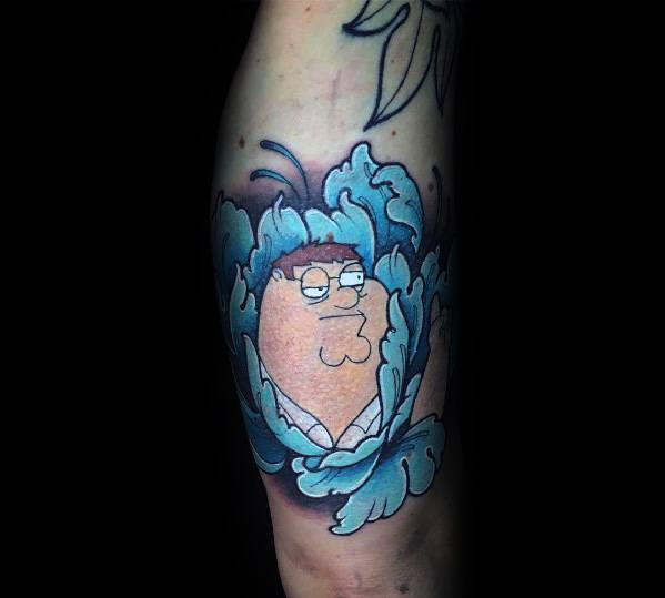 Tattoo of Peter Griffin from Family Guy blending into blue bushes, referencing the iconic "Homer Simpson backing into the hedge" meme.