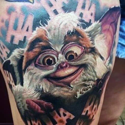 Realistic Gizmo tattoo with a mischievous grin, surrounded by 'HA' text, blending cuteness with a hint of chaos.