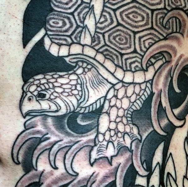 Black and grey Japanese turtle tattoo with intricate shell patterns and flowing waves, symbolizing strength, longevity, and resilience.