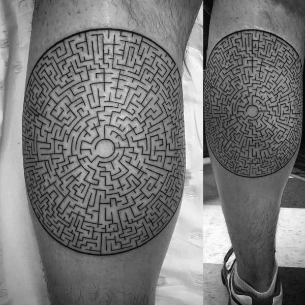 Intricate circular labyrinth tattoo on a man's thigh, featuring a highly detailed maze pattern with a small central point and bold black outlines.