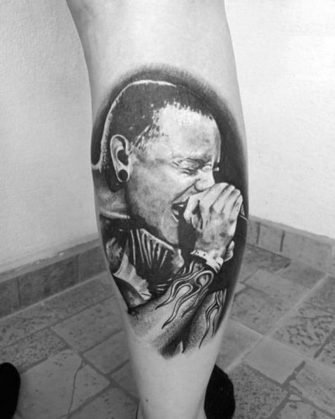 Black and gray tattoo of Chester Bennington passionately singing, featuring detailed shading and his iconic flame wrist tattoo.
