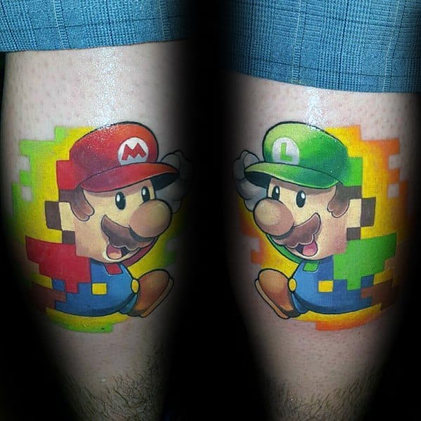 Vibrant tattoos of Mario and Luigi in pixel-art style, each with a colorful blocky background, inked symmetrically on both legs.