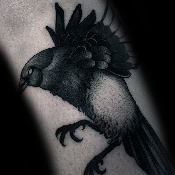 Black and gray magpie tattoo on forearm, featuring the bird in mid-motion with detailed feathers and shading for a bold, dynamic look.