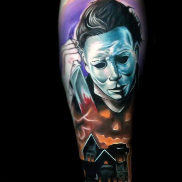 Vibrant Michael Myers tattoo featuring his eerie mask, a bloody knife, a haunted house, and a glowing jack-o'-lantern for a chilling effect.