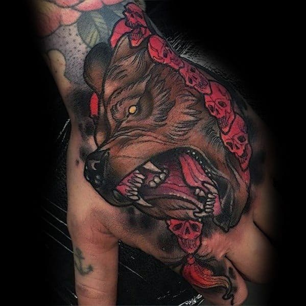 Neo-traditional bear tattoo on the hand featuring a snarling bear with piercing yellow eyes, bold shading, and a red skull-adorned chain.
