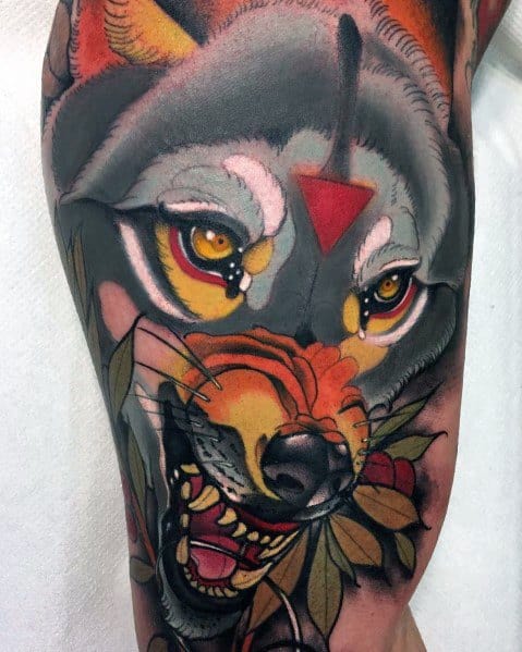 Neo-traditional tattoo of a snarling wolf with golden eyes, bold red markings, vibrant shading, and intricate leaf details for a fierce design.