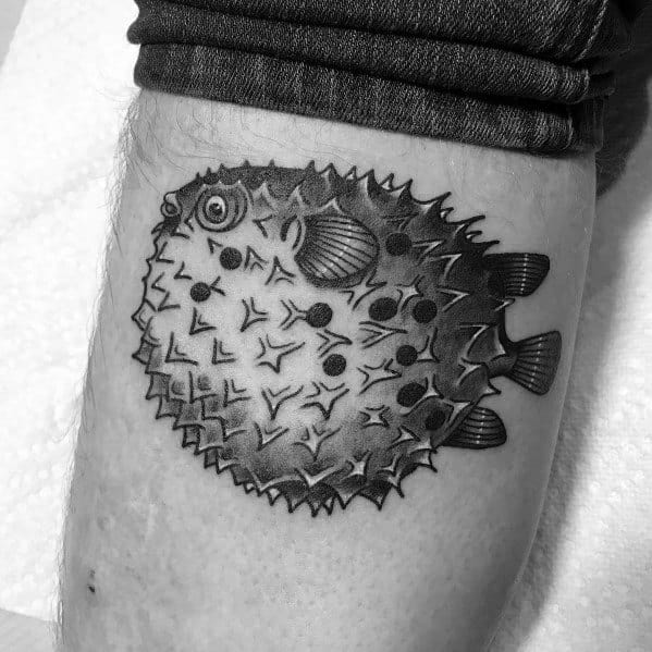 Black and grey pufferfish tattoo with bold shading and intricate spine details, creating a textured and dynamic underwater look.