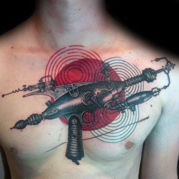 Intricate black and grey ray gun tattoo across the chest, featuring fine details, futuristic elements, and bold red concentric energy waves.