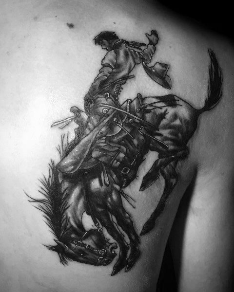 Realistic black and grey tattoo of a cowboy riding a bucking horse, featuring intricate details, dynamic motion, and expert shading for depth.