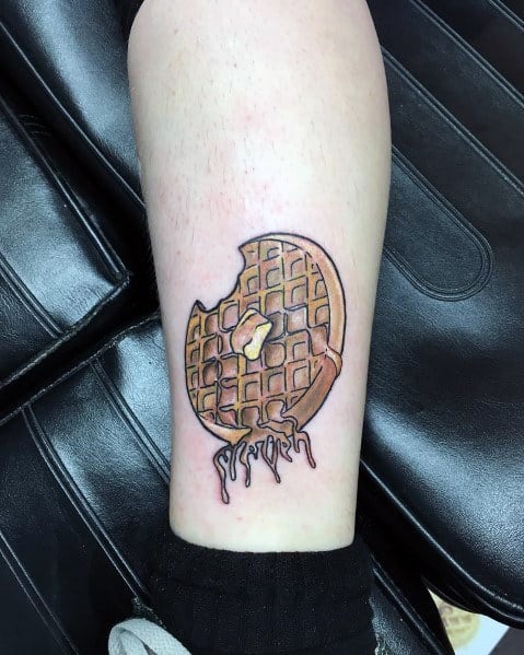 Realistic waffle tattoo with a bitten edge, melted butter, and dripping syrup, creating a bold and detailed breakfast-inspired design.